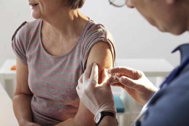 רופא נותן לאישה מבוגרת חיסון נגד שפעת 